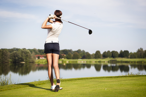 Woman golfer swinging golf club